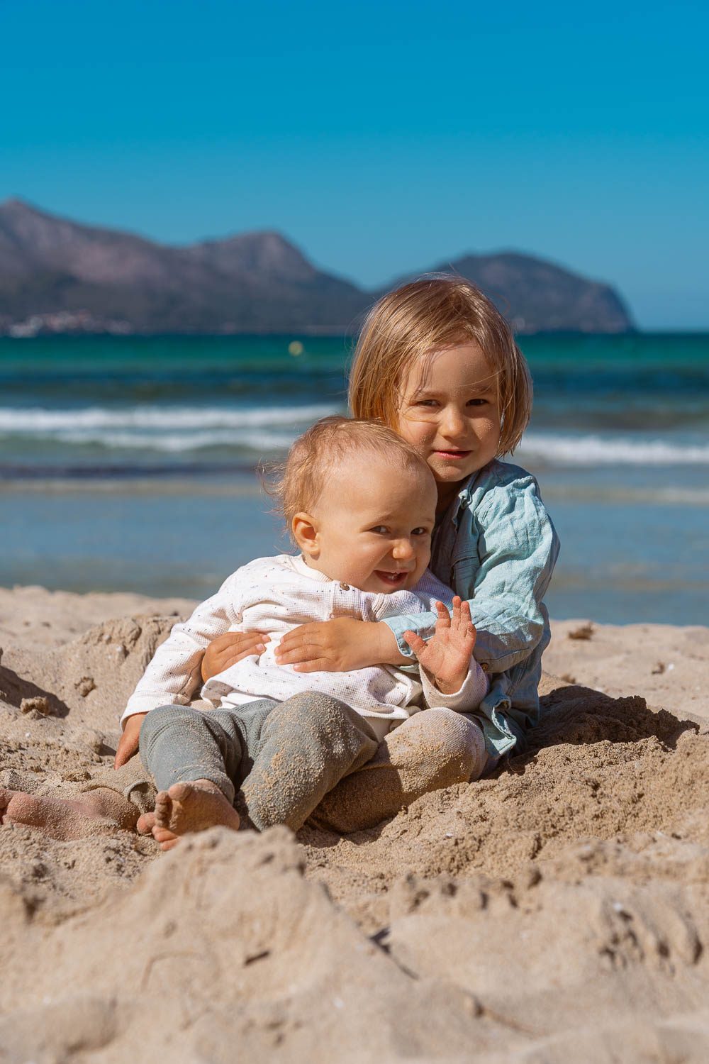 Familien Foto Mallorca - Kind im Sand, Eltern schauen lächelnd zu